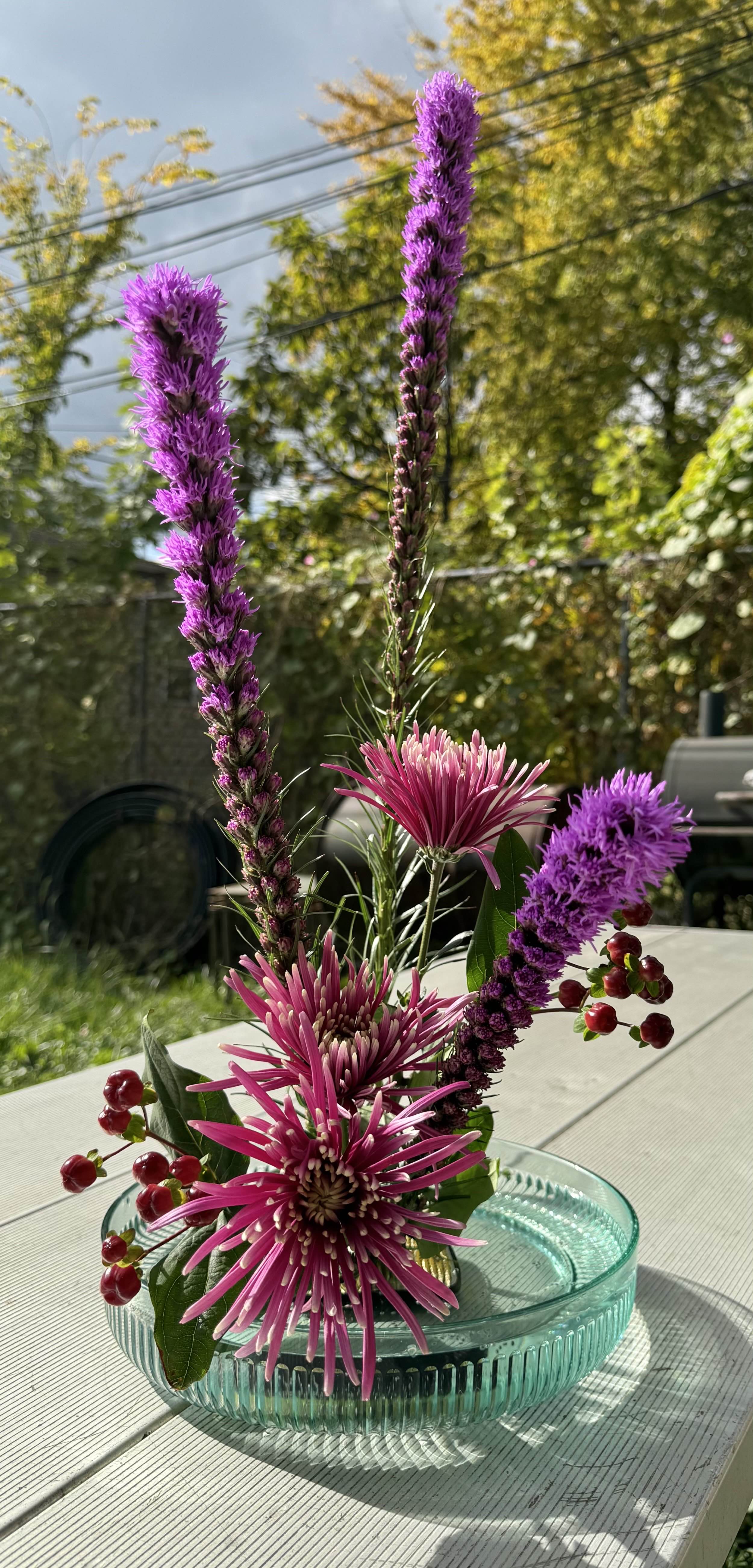 Image of rebuilt arrangement.
Outside, on a picnic table, surrounded by other foliage on a sunny day.
